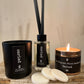 a gift box containing a glass reed diffuser, a matt black glass candle a copper tin candle and a pack of wax melts all scented with black pomegranate all labelled cariad